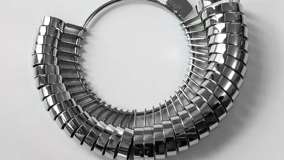 A jeweler's set of polished metal ring sizers of increasing size, held together on a metal ring