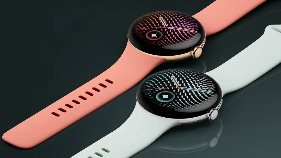 Two Google Pixel Watch 5 watches on a dark glossy surface, one with a coral band and a gold-toned case and one with a pale green-gray band and a silver-toned case, both showing a dotted radiating watch face