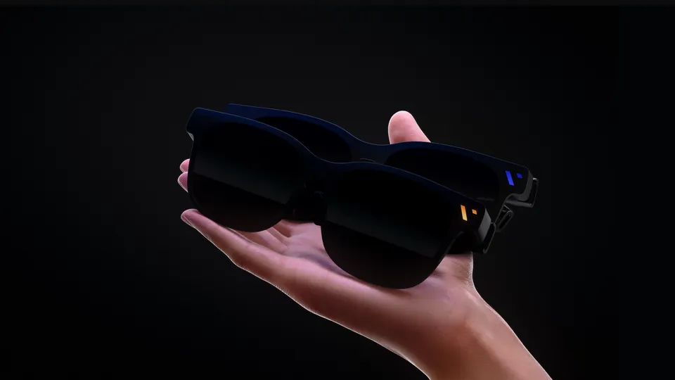 Two VITURE display glasses with dark frames held in an open hand against a black background