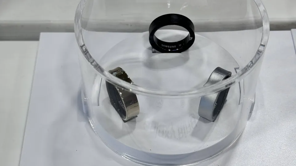 Three Samsung Galaxy Rings in black, gold and silver titanium inside a clear acrylic display case
